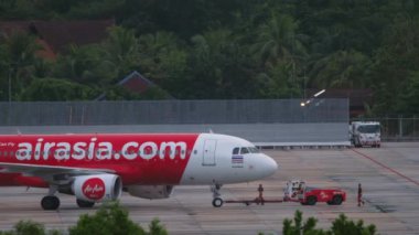 PHUKET, THAILAND - NOVEMBER 28, 2019: Tractor towing Airbus A320 of AirAsia at Phuket airport. Tourism and travel concept