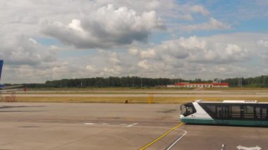 MOSCOW, RUSSIAN FEDERATION - JULY 24, 2021: Apron bus goes to the terminal. Passenger plane of Ural Airlines on the platform. Airport employee serving the plane