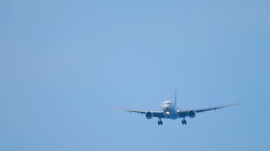 Front view of jet passenger plane in the blue sky. Airliner descending for landing. Unrecognizable plane flies, arriving. Tourism and travel concept