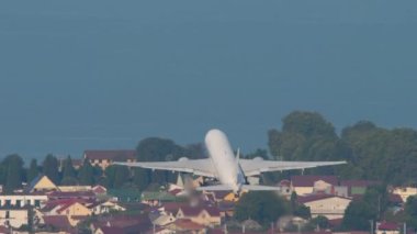 Widebody passenger airplane climb after takeoff, fly away, long shot. Airliner in the blue sky. Plane departure