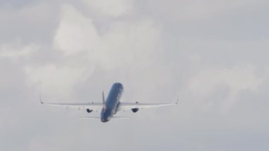 Rear view, a jet plane flies away, gaining altitude. Unrecognizable passenger airliner departure