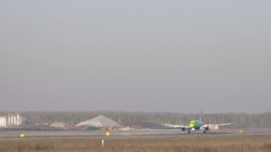 Long shot through the haze, airplane braking after landing on the runway. Tourism and travel concept