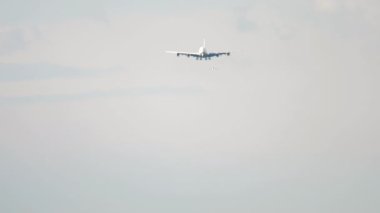 Widebody aircraft approaching landing, long shot. Airplane descending, view through haze. Tourism and aviation concept