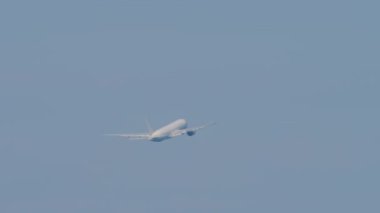 Widebody plane climbing after takeoff, fly away, long shot. Airliner in the blue sky. Airplane flying, side view