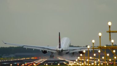 Airplane landing, touching down and braking with smoke. Landing lights illuminate the runway. Cinematic footage of aircraft flight arrival
