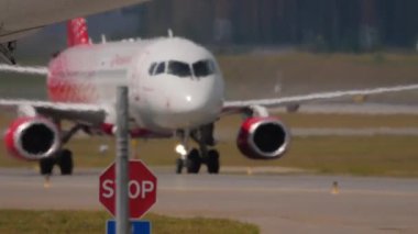 MOSCOW, RUSSIAN FEDERATION - JULY 29, 2021: Passenger plane of Rossiya taxiing to Sheremetyevo airport, Moscow. Haze on the airfield, aircraft blur. Stop sign on the taxiway