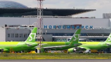 NOVOSIBIRSK, RUSSIAN FEDERATION - JULY 15, 2022: Plane of S7 Airlines taxiing on the runway at Tolmachevo airport. Row of C7 Airlines aircraft at the terminal. Tourism and travel concept