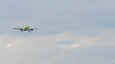 Jet plane with Green livery in the sky. Airplane approaching for landing, front view. Slow motion, airliner is flying