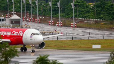 PHUKET, THAILAND - DECEMBER 02, 2016: Airbus A320 of AirAsia taxiing to the runway, Phuket Airport. Rainy day, wet airfield. Tourism and travel concept