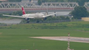 SOCHI, RUSSIA - AUGUST 03, 2022: Widebody plane Boeing 777 of Nordwind Airlines landing at Sochi airport. Airplane on the background of the city. Tourism and travel concept