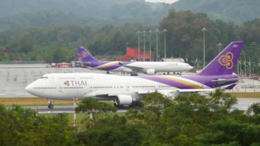 PHUKET, THAILAND - DECEMBER 02, 2016: Plane of Thai Airways speed up before take off at Phuket airport, side view. Jumbo jet departure. Airfield, palm trees