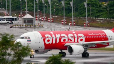 PHUKET, THAILAND - DECEMBER 02, 2016: Airplane of AirAsia on runway before takeoff at Phuket Airport. Rainy day, wet airfield. Tourism and travel concept