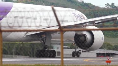 PHUKET, THAILAND - DECEMBER 05, 2016: Huge wide-body Boeing 777 of Thai Airways departure, Phuket airport, view through the fence. Tourism and travel concept