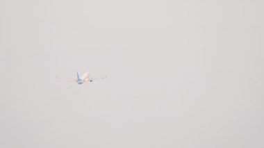 Airplane ascend towards clouds. Passenger airliner climb after takeoff, rear view long shot. Airplane fly away. Aviation and travel concept