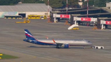 SOCHI, RUSSIA - AUGUST 04, 2022: Airplane towing at the airport, Aeroflot and tractor on the airfield. Sochi International Airport