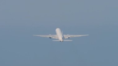 Widebody passenger airplane climb after takeoff, fly away, long shot. Airliner in the blue sky. Plane departure