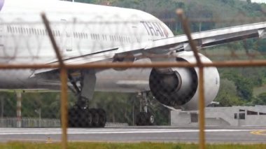 PHUKET, THAILAND - DECEMBER 05, 2016: Widebody plane Boeing 777 of Thai Airways on runway, Phuket airport, view through the fence. Tourism and travel concept