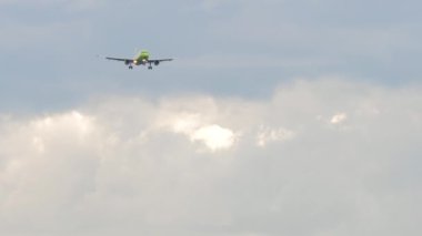Slow motion footage of an airplane approaching to land, long shot. Jet plane in the cloudy sky