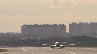 Rear view of a jet plane takeoff, departure at sunrise or sunset. Sun glare on an airplane. Tourism and travel concept