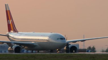 KAZAN, RUSSIA - AUGUST 05, 2022: Airbus A330 Nordwind airline, beautiful sunset or sunrise background. Passenger board on the taxiway at the airport. Tourism and travel concept