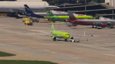 SOCHI, RUSSIA - JULY 28, 2022: Tractor towing aircraft S7 Airlines on the runway at Sochi airport, long shot from a tripod. Tourism and travel concept