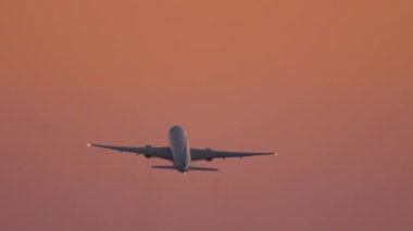 Jet civil aircraft climb, flies in the sunset beautiful sky, long shot. Airliner silhouette departure. Tourism and travel concept