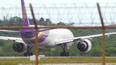 PHUKET, THAILAND - DECEMBER 05, 2016: Widebody passenger plane Boeing 777 of Thai Airways departure, Phuket airport, view through the fence. Tourism and travel concept