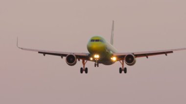 KAZAN, RUSSIA - AUGUST 05, 2022: Cinematic shot of aircraft S7 Airlines flies. Front view long shot of jet plane approaching to landing. Airplane descent, sunset or dawn