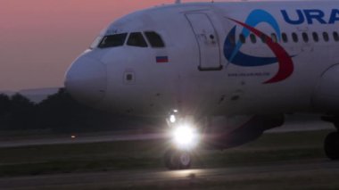 KAZAN, RUSSIA - AUGUST 05, 2022: Closeup shot of Airbus A320 Ural Airlines taxiing on the runway, sunset or dawn. Airplane on the taxiway at sunrise. Tourism and travel concept