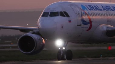 KAZAN, RUSSIA - AUGUST 05, 2022: Commercial plane Airbus A320 of Ural Airlines taxiing on the runway, sunset or dawn. Airplane on the taxiway at sunrise. Tourism and travel concept