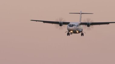 KAZAN, RUSSIA - AUGUST 05, 2022: Passenger aircraft ATR-72 of UTair flies. Turboprop plane landing. Airplane descent, sunset or dawn