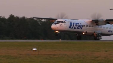 KAZAN, RUSSIA - AUGUST 05, 2022: Passenger aircraft ATR-72, RA-67685 of UTair arriving, touching and braking. Turboprop plane landing. Airplane descent, sunset or dawn