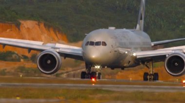 PHUKET, THAILAND - JANUARY 22, 2023: Passenger plane of ETIHAD landing, arrival at Phuket airport. Cockpit, close-up shot, front view. View through the fence. Airplane on the airfield. Travel concept