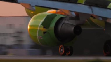 Close-up of a commercial plane braking after landing at an airport at sunset. Vacation, travel and aviation concept