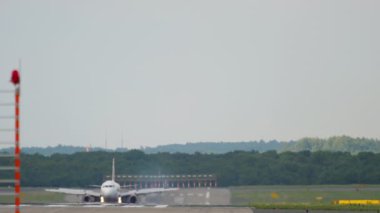 Tourism and travel concept. Passenger jet airplane arriving at Dusseldorf airport. Long shot, the aircraft braking after landing