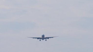 Front view long shot of an unrecognizable jet aircraft approaching to land. Airplane flies, blue sky background. Travel concept