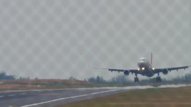 Airplane landing, touching the runway and braking. Flaps up. Aircraft arrival. Airfield through the fence