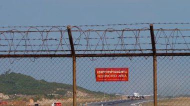 PHUKET, THAILAND - JANUARY 22, 2023: Red sign Restricted area. Long shot of jet airplane AzurAir take off, departure at Phuket airport. Charter passenger flight. Travel concept