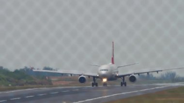 PHUKET, THAILAND - JANUARY 24, 2023: Passenger plane Airbus A330 of Turkish Airlines braking after landing at Phuket Airport. Passenger flight, airfield through the fence. Tourism travel concept