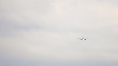 Passenger jet approaching before landing against a cloudy gray sky. Tourism and aviation concept