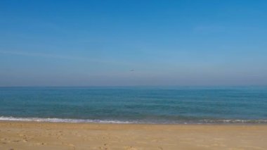 Footage of jet plane approaching to land. Cinematic shot of an airliner in the blue sky over the sea. Airplane flies over the ocean. Tourism and travel concept