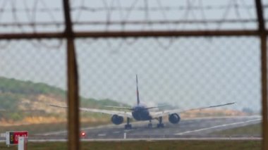 Rear view through the airport fence of a wide-body passenger plane taking off, flying away. Aircraft departure