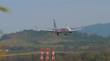 PHUKET, THAILAND - FEBRUARY 08, 2023: Footage of a passenger Boeing 737 Thai Lion landing at Phuket Airport. Aircraft approaching, side view. Tourism travel concept