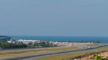 PHUKET, THAILAND - FEBRUARY 08, 2023: Panoramic view of the airfield Phuket airport. Jet plane take off. Seascape. Airplane speeding up, long shot on the runway