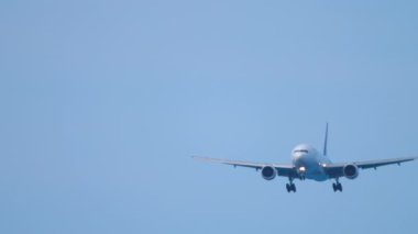 Front view of jet passenger jet plane in the blue sky. Airliner approaching for landing. Unrecognizable plane flies, arriving. Tourism and travel concept
