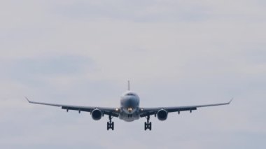 Jet aircraft approaching to land. Airplane flies, blue sky background. Airliner silhouette descending. Travel concept