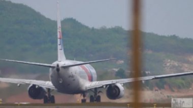 PHUKET, THAILAND - JANUARY 28, 2023: Boeing 737 of Malaysia Airlines acceleration before takeoff at Phuket Airport. Airplane departure. Aircraft on the runway, rear view