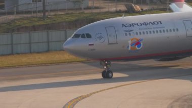 PHUKET, THAILAND - FEBRUARY 08, 2023: Airbus A330 of Aeroflot taxiing at Phuket Airport, middle shot. Airplane turns on the runway, sun glare. Footage aircraft on the taxiway