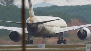 PHUKET, THAILAND - JANUARY 30, 2023: Plane Boeing 787 Dreamliner of Etihad Airways speed up before take off at Phuket airport, rear view. Passenger flight departure. Airplane on the runway