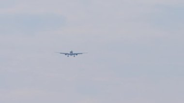 Footage of an unrecognizable jet aircraft approaching to land. Airplane flies, blue sky background. Airliner silhouette descending, wide angle view. Travel concept
